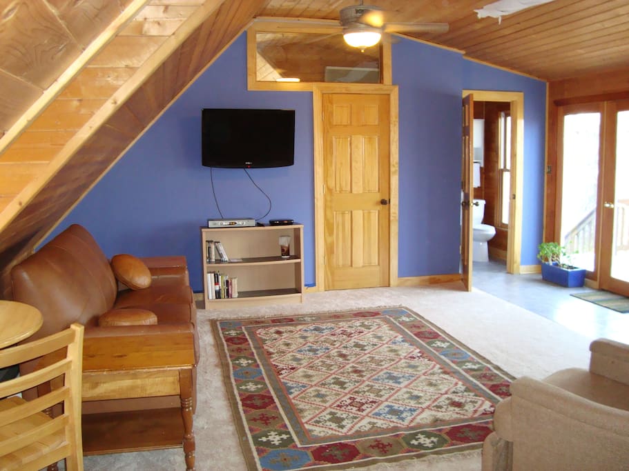 "Nest" upstairs of woodland cottage, with cathedral ceiling and window wall opening to deck and exterior stairs, and doors leading to half bath and to interior stairway. Wifi with high speed internet, tv with Roku box for streaming, leather sofa bed, ceiling fan, light, and heater