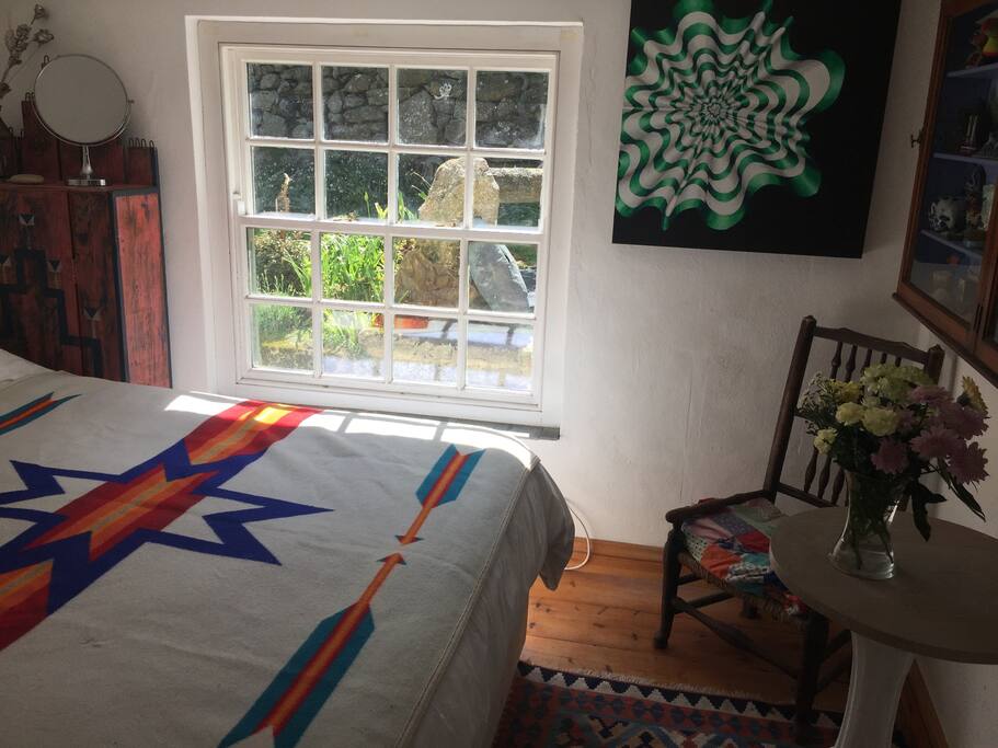 Small cottage bedroom with Queensize bed.view from the window walled garden and stone well.
