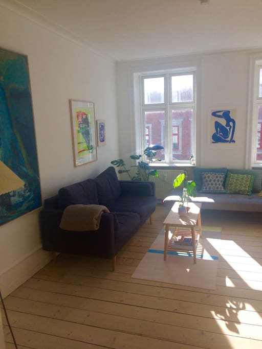 Big, bright and colorful living room with 2 couches and a lot of art on the walls.