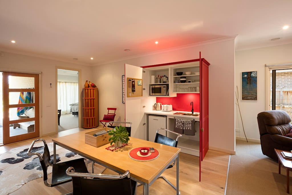 A stylish kitchenette with sink, fridge, toaster, microwave and utensils.