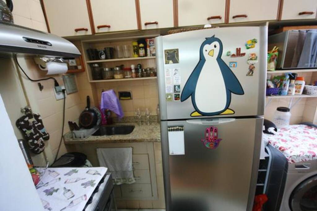 Cozinha com geladeira, fogão, microondas e armários.