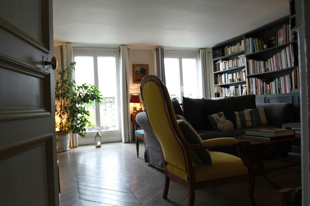The living room (parquet flooring) with 2 large windows with perfect condition facing due west with beautiful Paris view (Montmartre) from the big balcony (a small table and 2 chairs), including a Wood bookcase, a fireplace, a table for 6 and a queen size convertible sofa-bed.