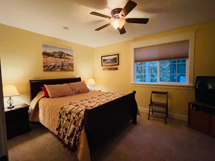 La camera da letto a tema "Oregon wine country" dell'ospite al piano superiore è semplicemente arredata con un letto a slitta queen-size e comodini abbinati, ventilatore/luce a soffitto, lampade da tavolo e armadio di grandi dimensioni.
