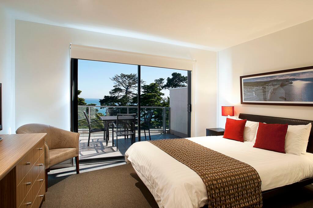 Queen bed in the main area looking over balcony