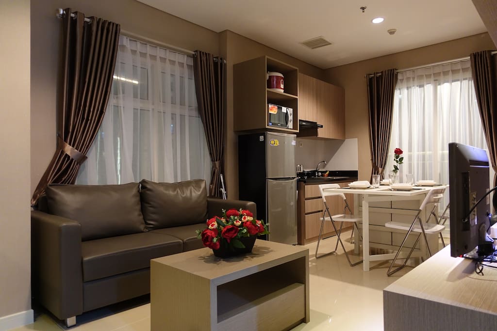 Living Area equipped with comfortable sofa, TV, Air Conditioning and Coffee Table.