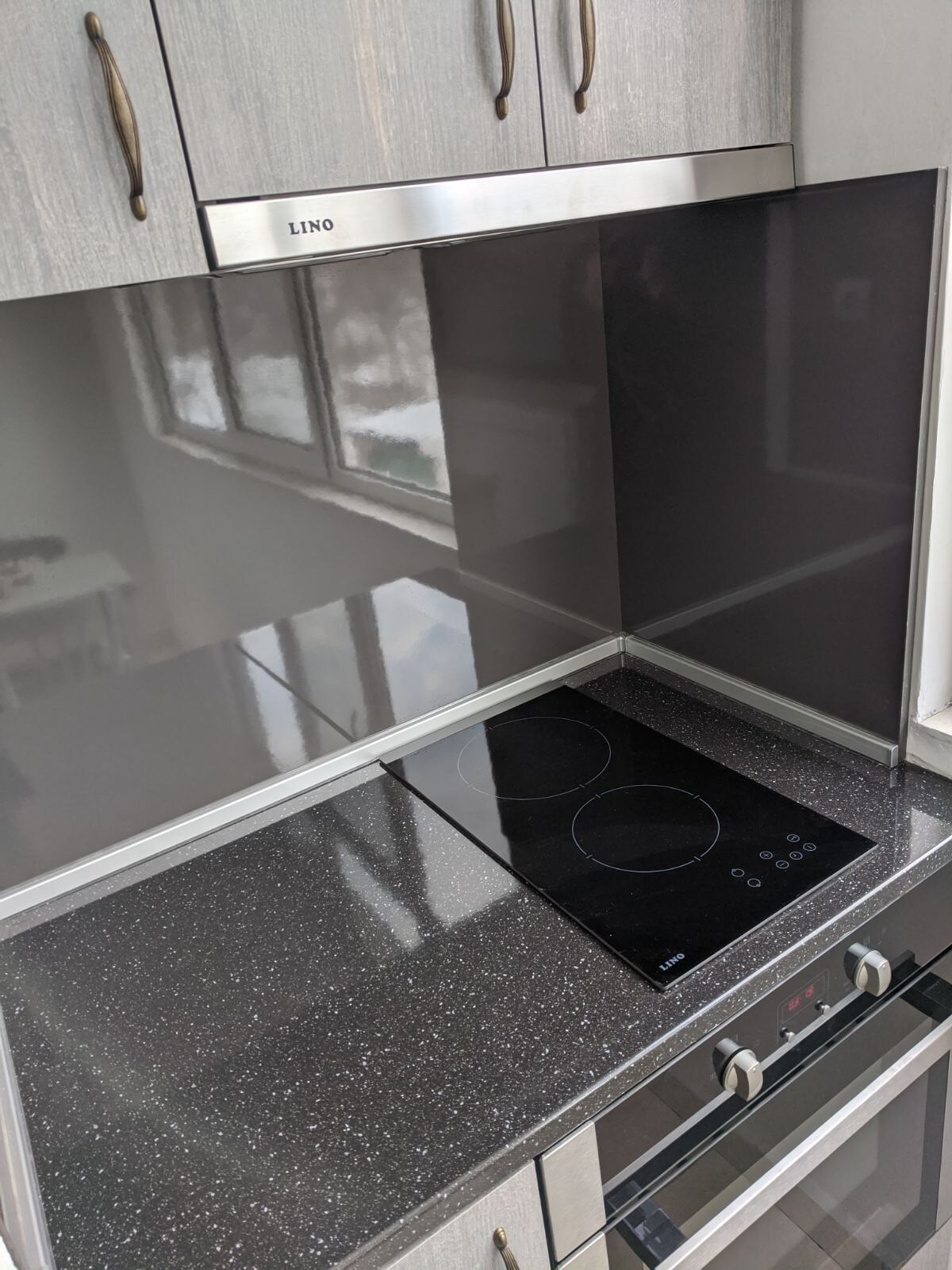The equipped kitchen features a sleek black countertop with an induction cooktop and an oven below. Natural light is brought in through multiple windows, highlighting the minimalist cabinetry and modern finishes.