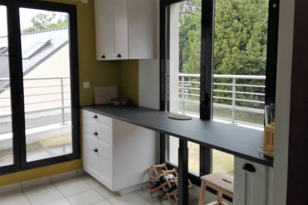 La cuisine avec une baie vitrée qui donne accès sur la terrasse