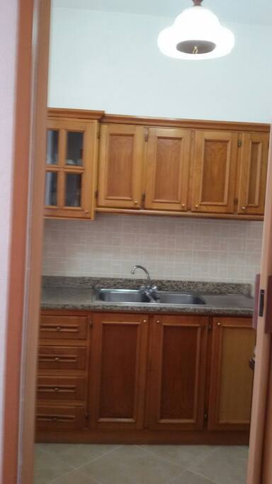 cucina in legno con lavandino, piano cottura, dispensa completa di stoviglie e pentole