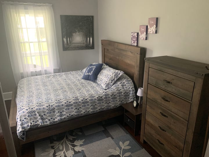 First floor bedroom with queen bed and tall chest dresser. 