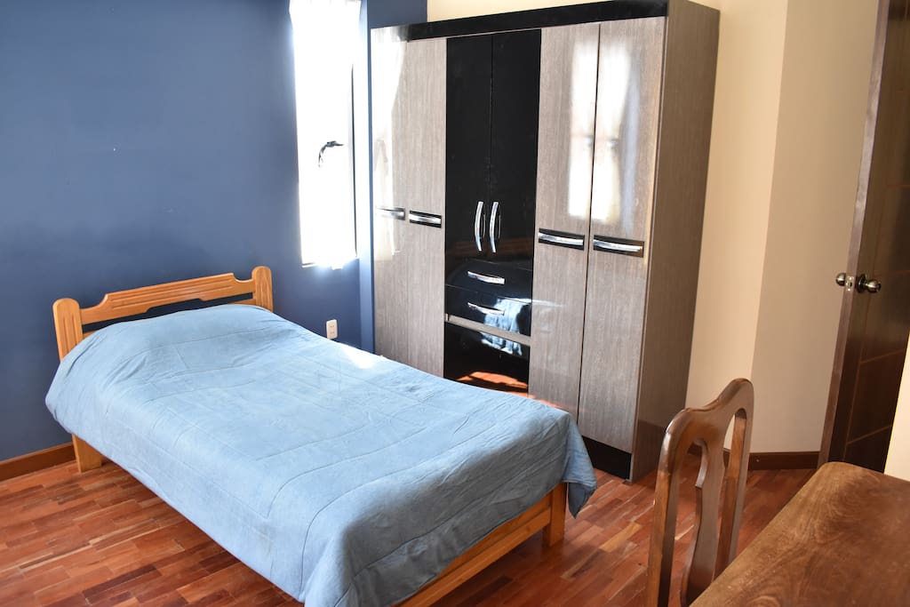 Dormitorio con cama simple, closet y escritorio.
