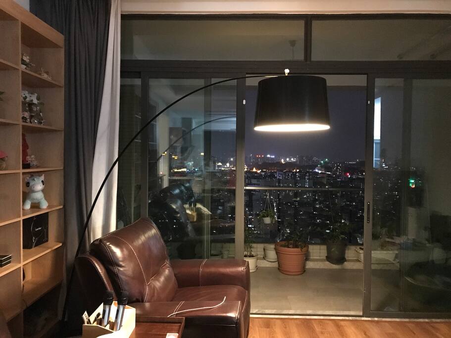 客厅亦铺装木地板宽敞舒适,配置芝华士真皮沙发、小米空气净化器、极米投影仪、Xbox体感游戏机、麦克风等。中山地标摩天轮在夜晚灯光闪烁,浪漫迷人