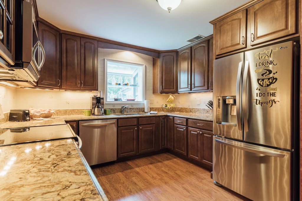 Kitchen with dishwasher, range, microwave, fridge, coffee maker, cooking and serving dishes and utencils
