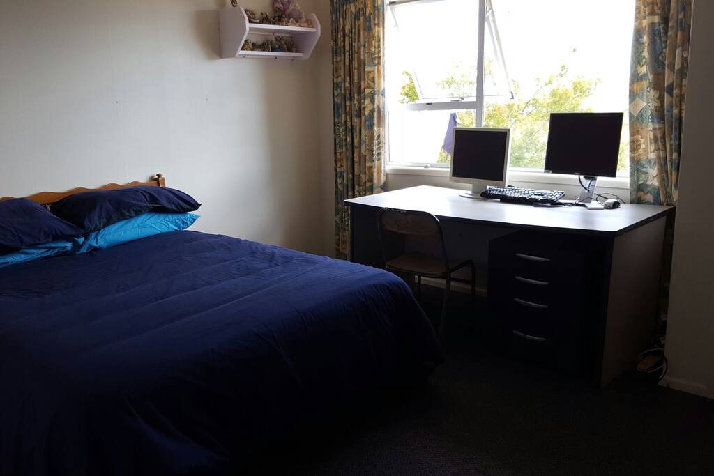 Large room with double bed, desk and dresser.