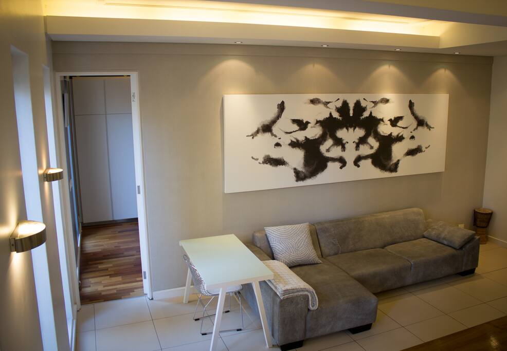 An overview of the spacious central living space, includes a flexible work space space, custom-designed leather sofa, 42" TV equipped with Netflix, and a high-speed fibre connection.