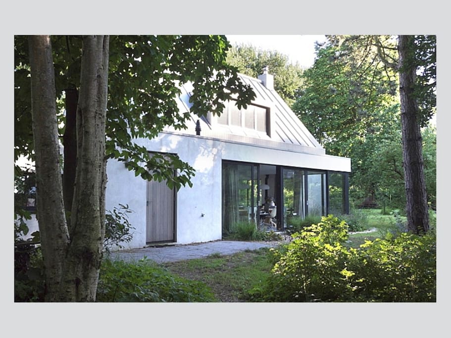 Achterkant van het huis, met rondom grote ramen en uitzicht op de grote tuin