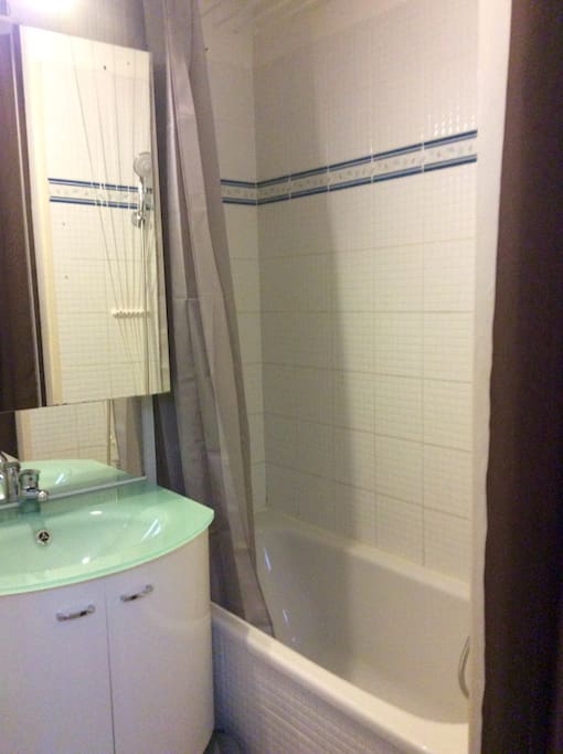 Salle de bain avec baignoire, étendoir à linge et machine à laver