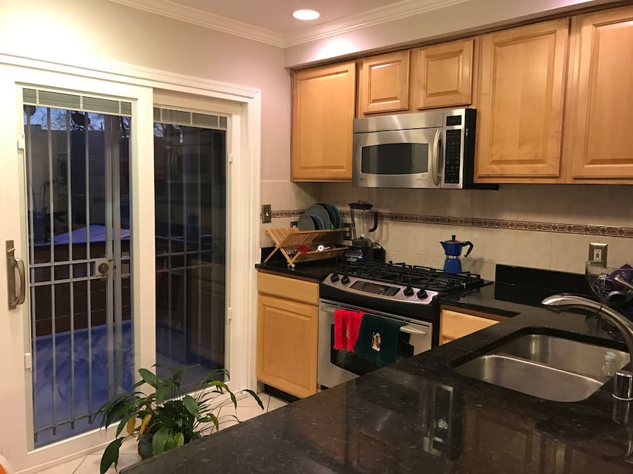 Spacious kitchen with granite countertops, oven, stove, fridge, freezer, various coffee makers, and stand mixer.