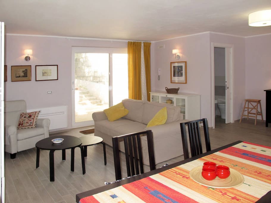 Soggiorno spazioso e luminoso con tavolo da pranzo e divano letto matrimoniale per 2 persone.
Spacious and bright living room with dining table and sofa bed for 2 people.