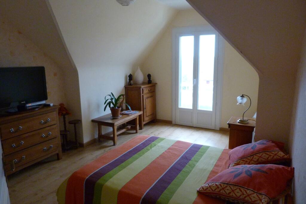 Chambre à l'étage avec balcon et télévision.