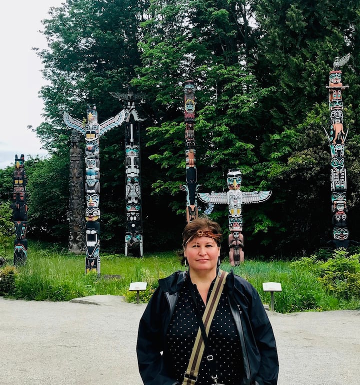 image of woman standing in front of indigenous totems