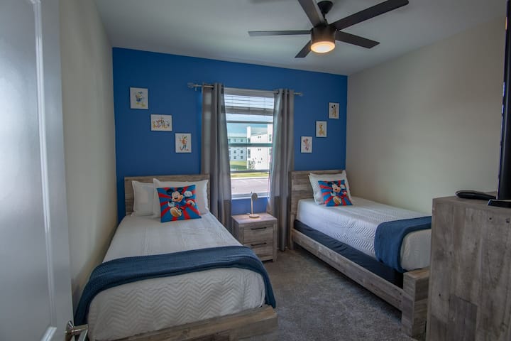 2 საწოლი და ტელევიზორი კიდოს ოთახში.