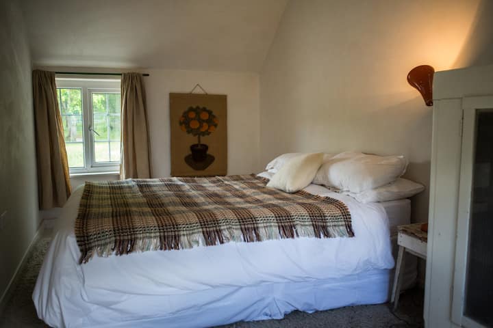 Bedroom with king-sized bed, deep memory foam mattress, goose down duvet, and 400 thread count Egyptian cotton  sheets, woollen Welsh blanket. Painted wooden floor and wool rug from Chile. Double aspect room with high ceiling and oak purlins. 