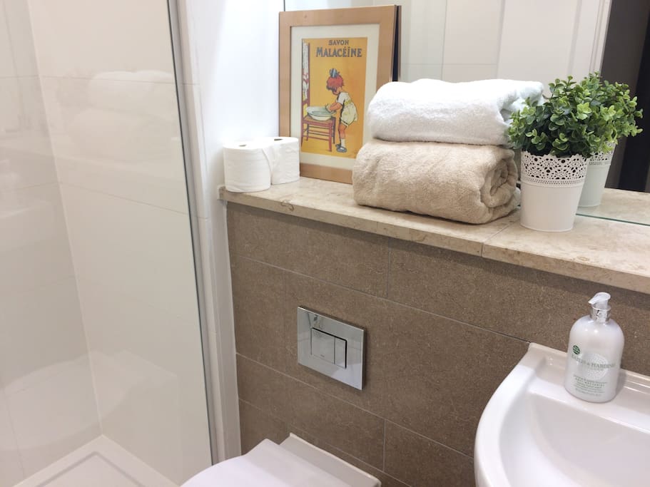 En suite bathroom with shower, fresh towels, hand soap, shower gel, shampoo, conditioner, toothpastes, sanitary products, razors, painkillers