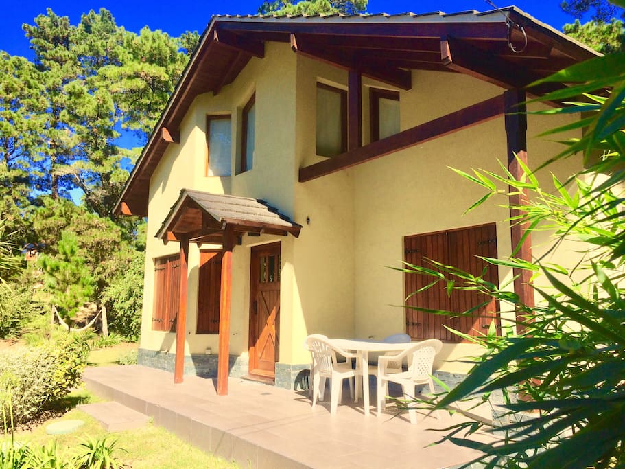 Deck en el frente de la casa con mesas y silla de exterior