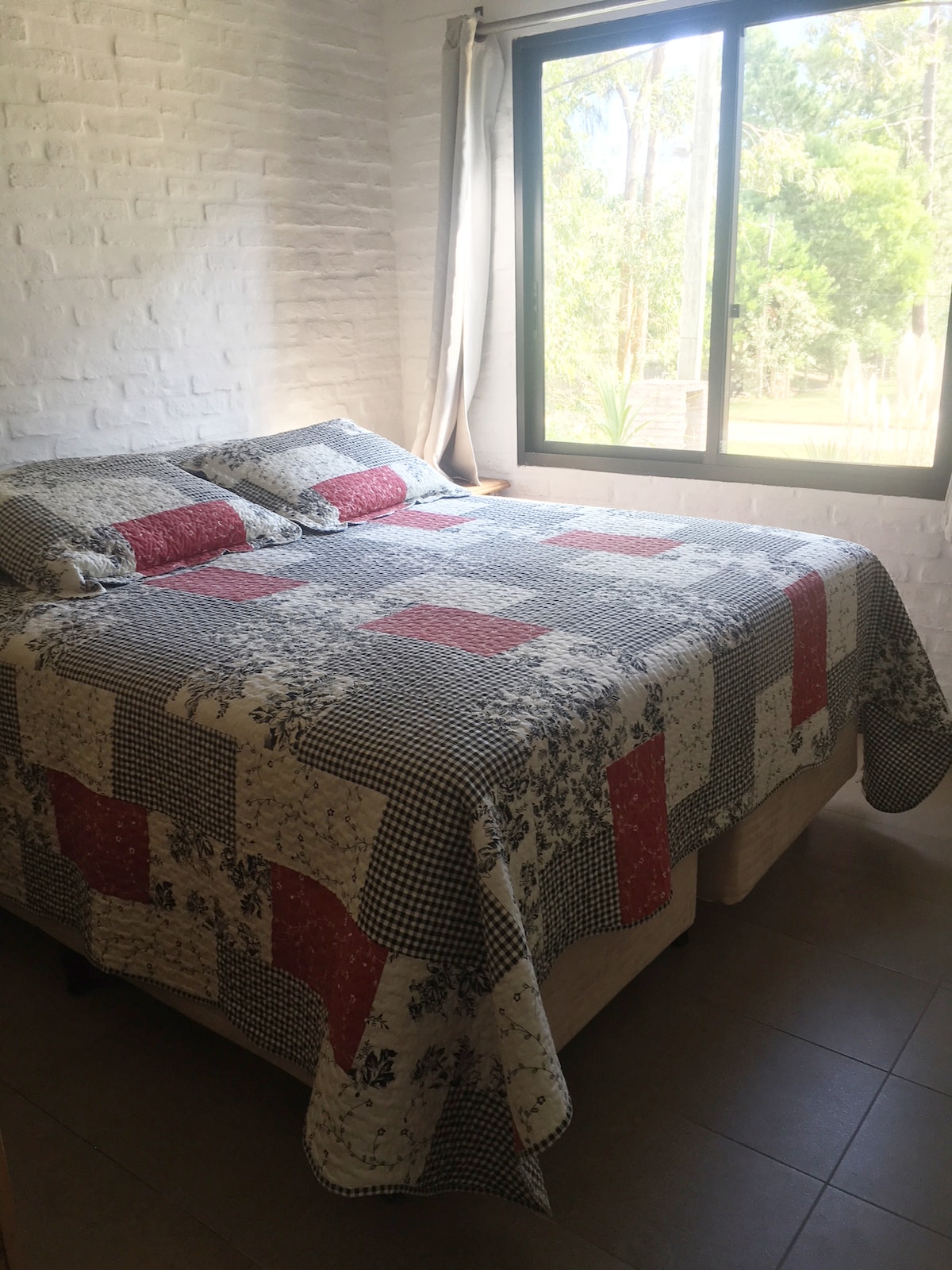 חדר שינה ראשי עם נוף ליער ומיטת קינג סייז עם מזרן איכותי למנוחה נוחה.