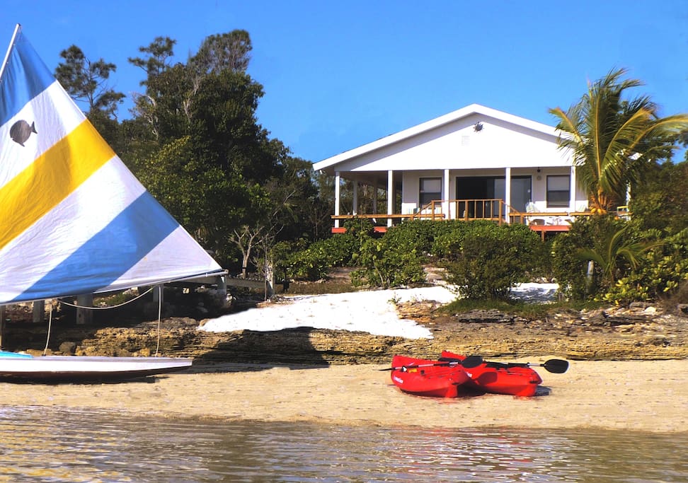 View of the beach, tropical landscaping and wrap around porch from the water.