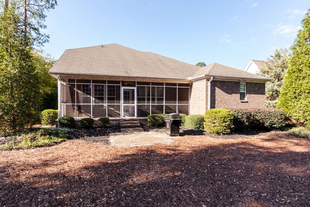 Backside of the house with screened in porch, grill, and outdoor seating.