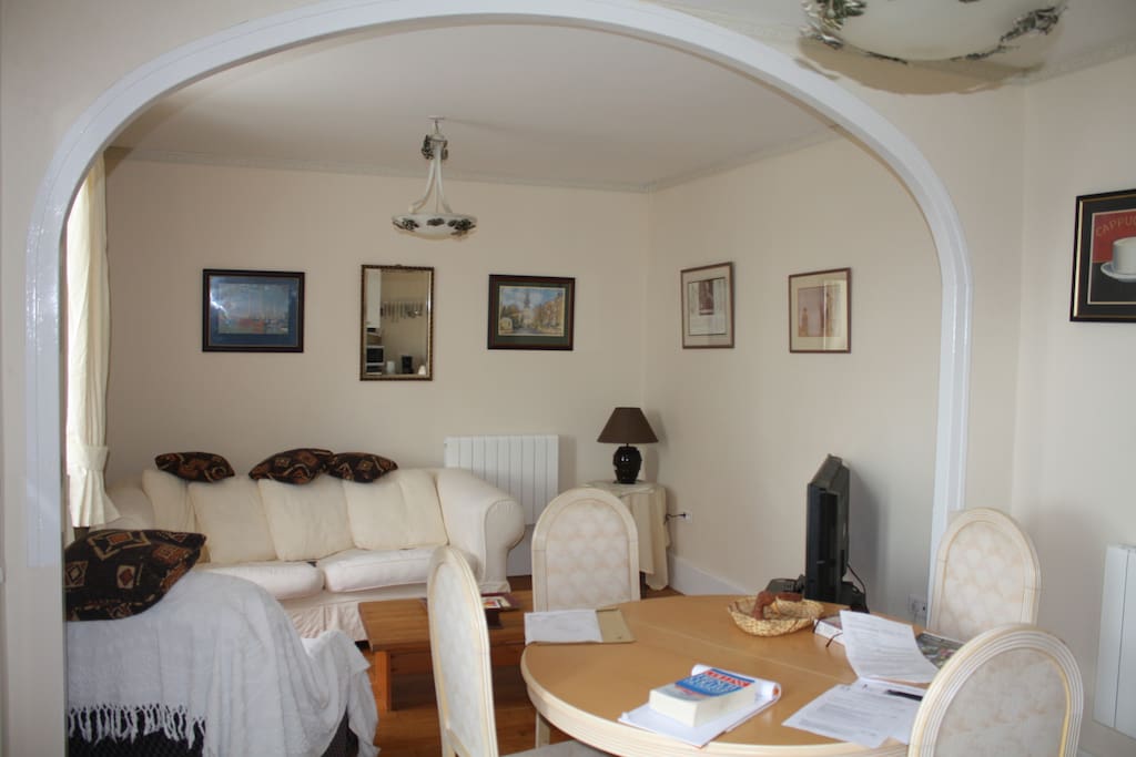 Spacious living and dining area with comfy chairs and TV