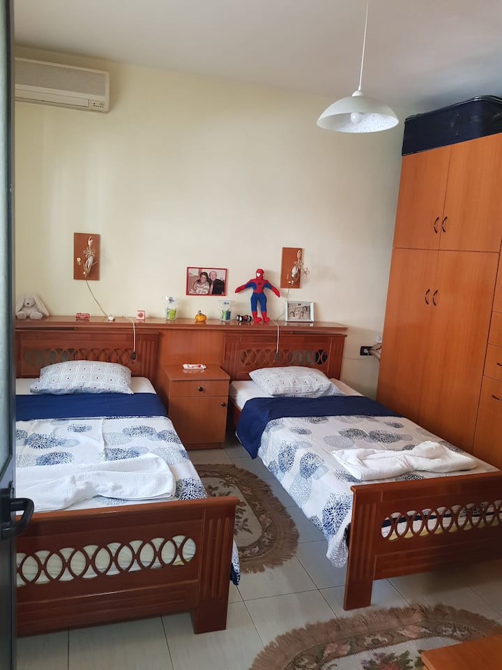 Chumba cha kulala kilichowekewa samani za wastani, chenye vitanda 2 vya mtu mmoja, kabati 1 kubwa na kabati 2 ndogo. Madirisha yana mapazia na pia vivuli dhidi ya jua.