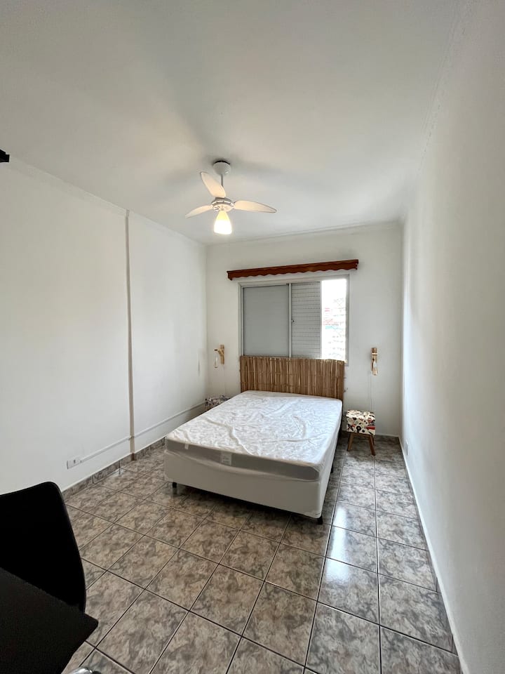 Chumba chenye kitanda cha watu wawili kilicho na meza 2, feni kwenye dari. Dirisha lenye chandarua cha usalama. 