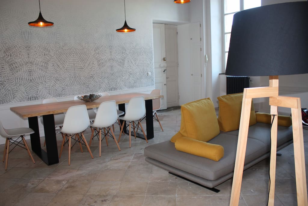 Salle à manger avec grande table plateau frêne, 8 chaises style Eames, canapé avec dossiers modulables.
