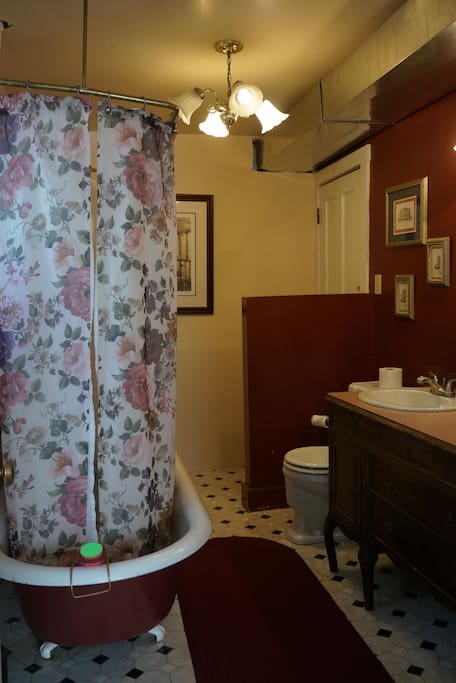 Attached private bathroom with shower over claw-foot tub, sink and toilet.