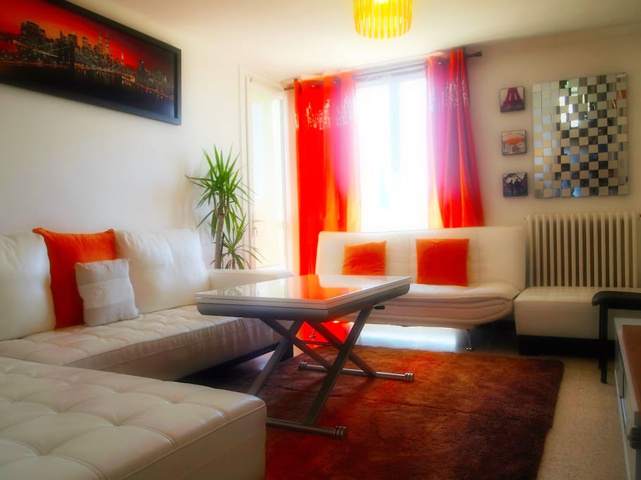 Salon avec un grand canapé d'angle en cuir blanc+écran plat+table de salle à manger extensible et un accès direct à la terrasse