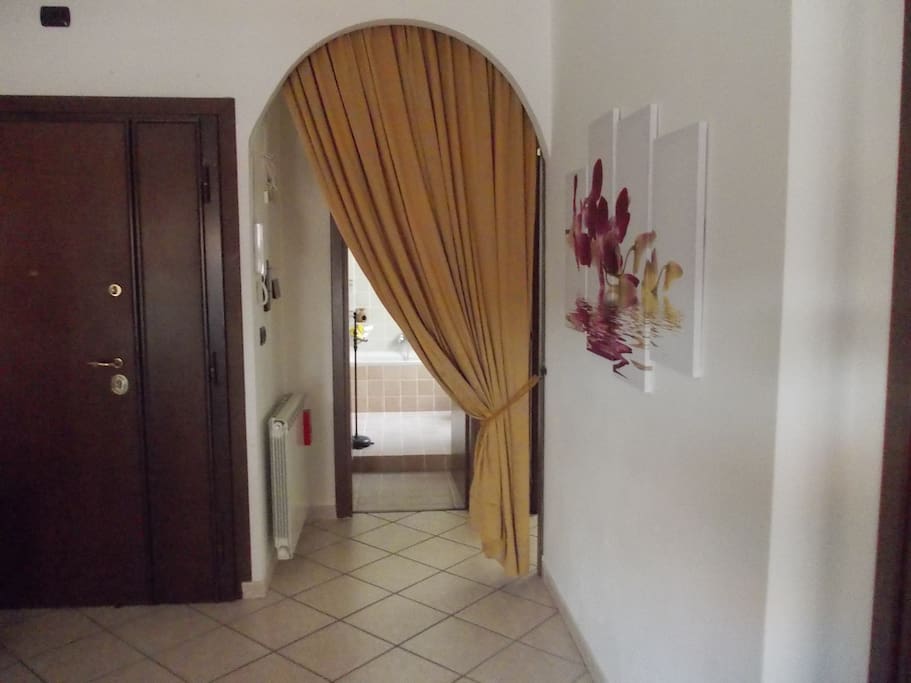 Porta d'ingresso e arco con tenda da cui si accede al bagno e alla camera da letto matrimoniale