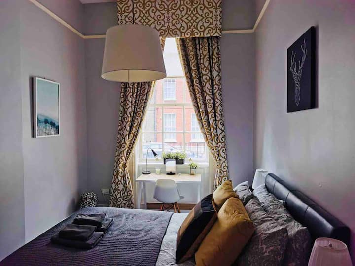 El dormitorio 1 es un dormitorio de estilo georgiano con techo alto, armario doble con perchas y secador de pelo, cómoda cama de 5F, 2 mesas laterales con lámparas de lectura y un escritorio frente a la ventana.