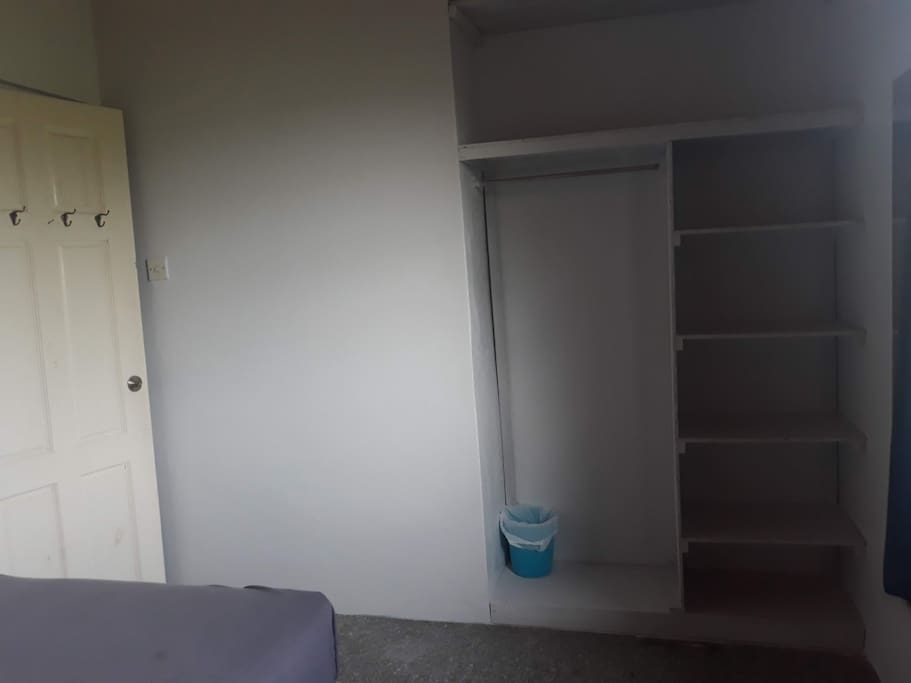 Freshly built closet. Bin and mirror. Hangers on door. Door with lock.