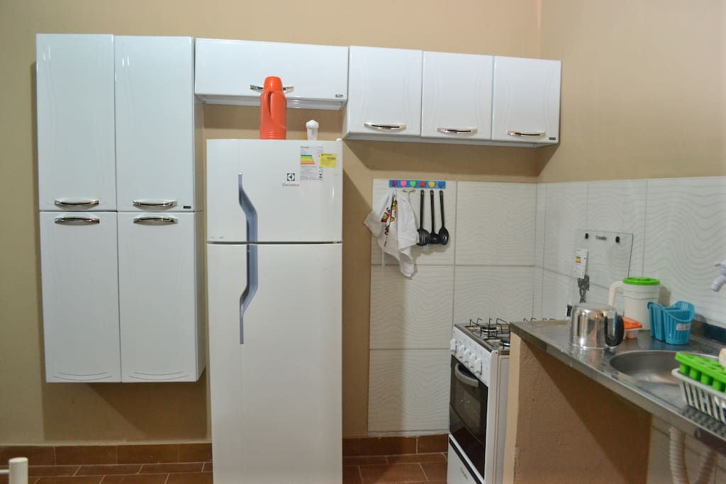 Cozinha com geladeira, fogão, armários, pia, e tudo mobiliado.