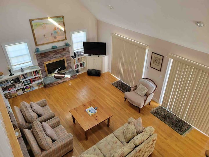 יורדים במדרגות לחדר הנהדר עם 2 סטים של דלתות הזזה מזכוכית שנפתחות אל הדק הענק; אח גז פעילה