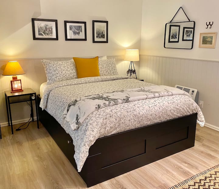 Dormitorio tipo estudio de concepto abierto con colchón tamaño queen nuevo y marco de cama de plataforma nuevo con cajones con ruedas.
