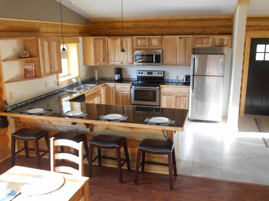 Beautiful new kitchen with stainless DW, fridge, micro, stove, counter bar, dishes, pans, utensils