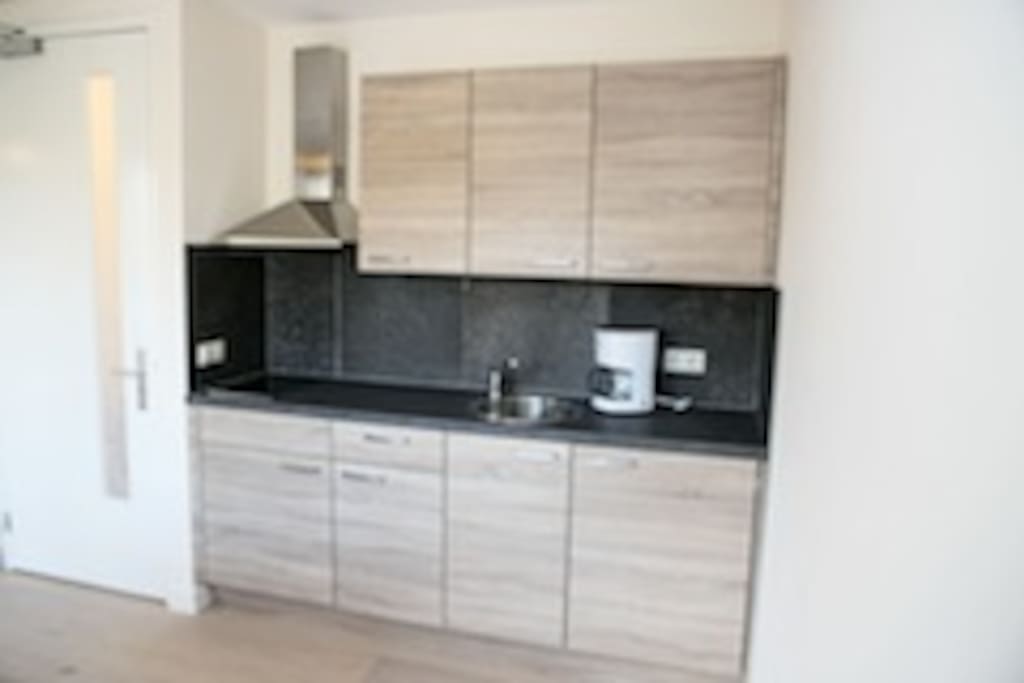Keuken met kookplaat, koelkast, afzuigkap, servies, bestek, pannen, koffieapparaat, tosti ijzer
