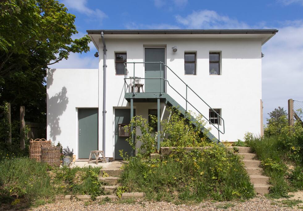 The unsual WW2 Lookout building with orginal features including metal stairs to the door. This warm south facing side catches the sun all year round.