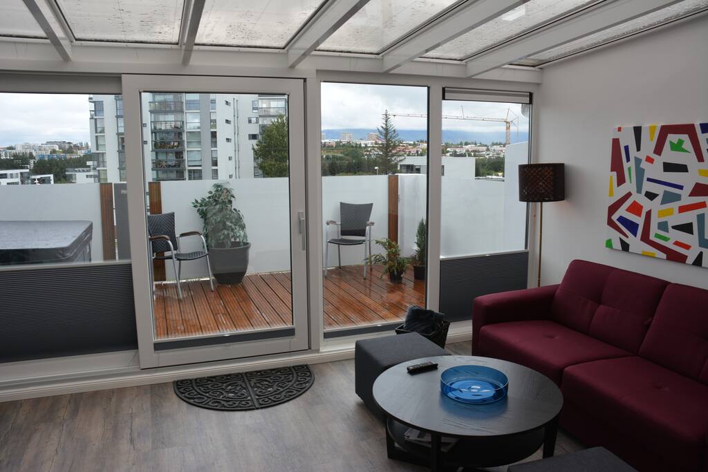 Living room with sofa bed and glass roof where you can enjoy the stars or Northern lights from inside and a terrace with hot tub that you can use in all kinds of weather.