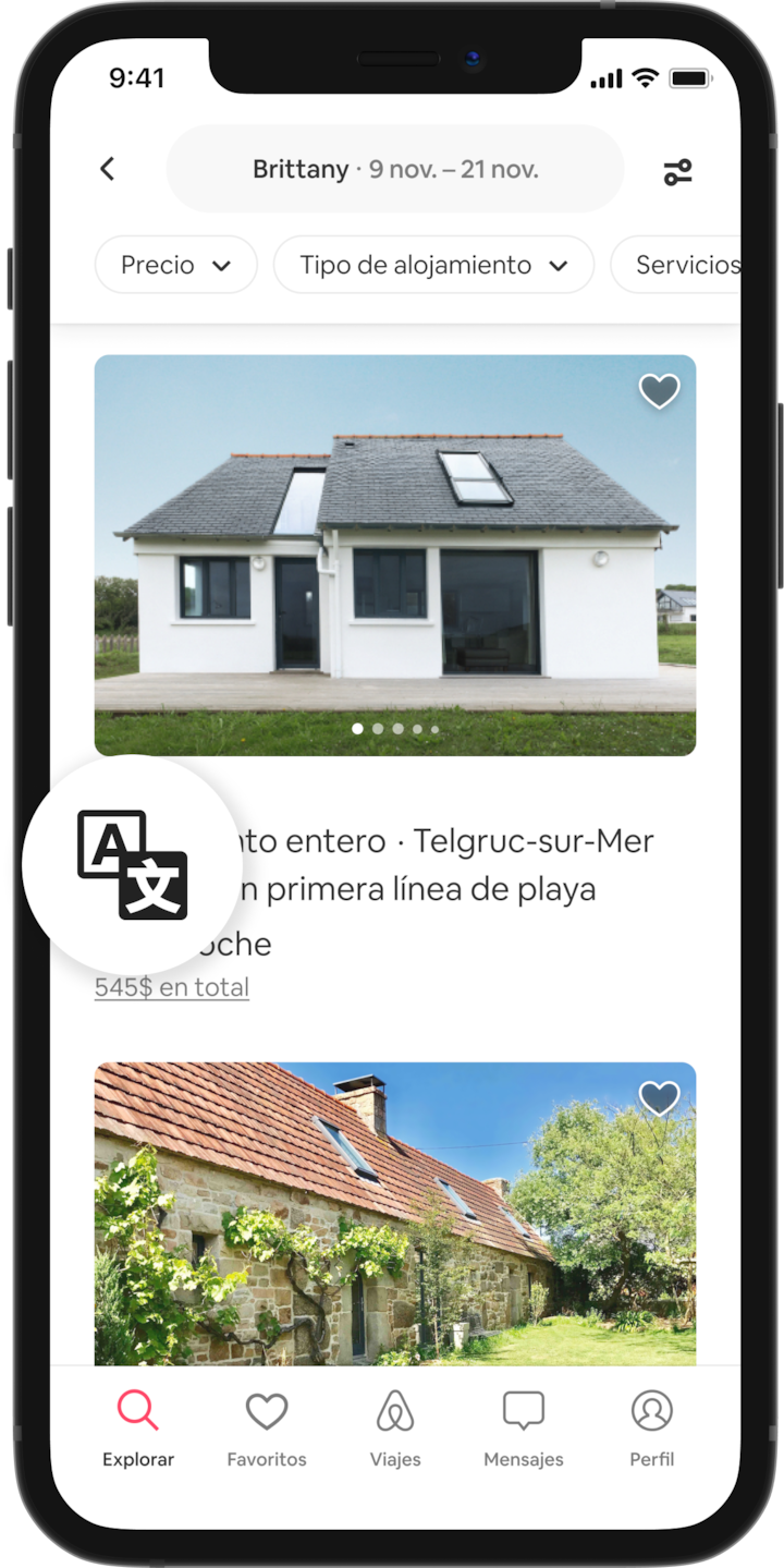 Un teléfono móvil muestra los resultados de una búsqueda de alojamientos en Bretaña, Francia. Hay un icono de traducción que aparece ampliado en un círculo.
