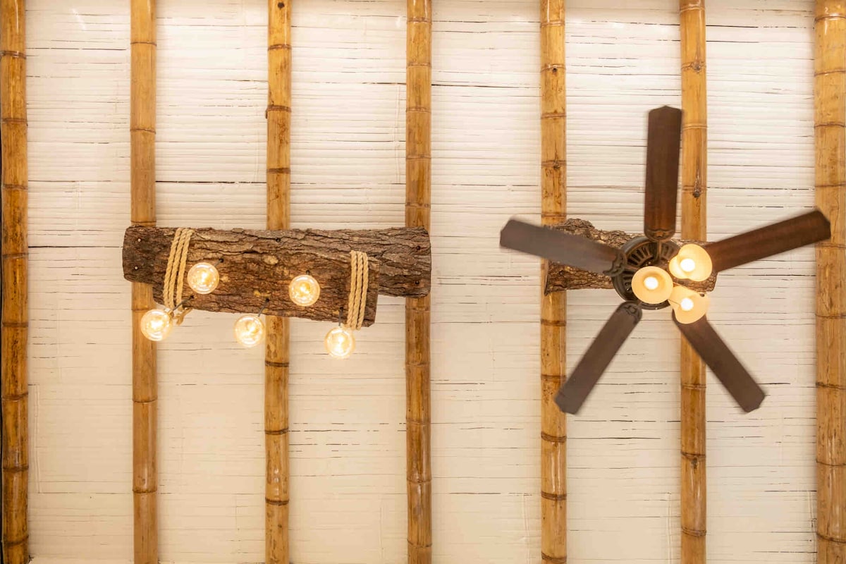 Natural wooden beams stretch across the ceiling, adorned with stylish light fixtures and a ceiling fan. The warm glow of the lights enhances the rustic elements of the cabin, while the fan adds a functional touch to the space.