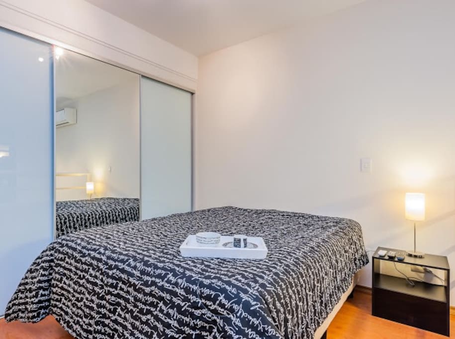 Quarto com cama queen size padrão hotelaria. Armários planejados 3 portas com espelho.